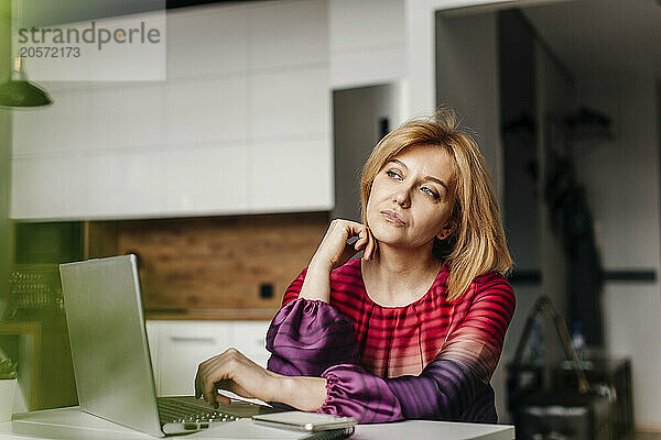 Contemplative freelancer with laptop at home