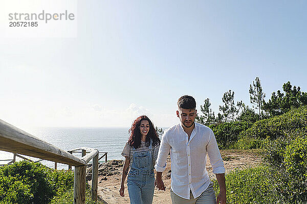 Couple holding hands and walking near railing