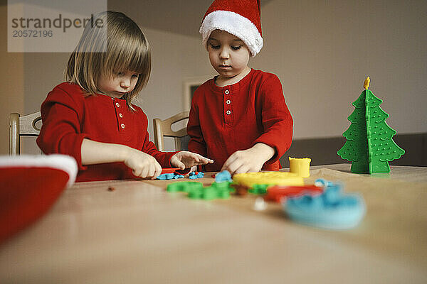 Brother and sister making Christmas decorations from plasticine at table