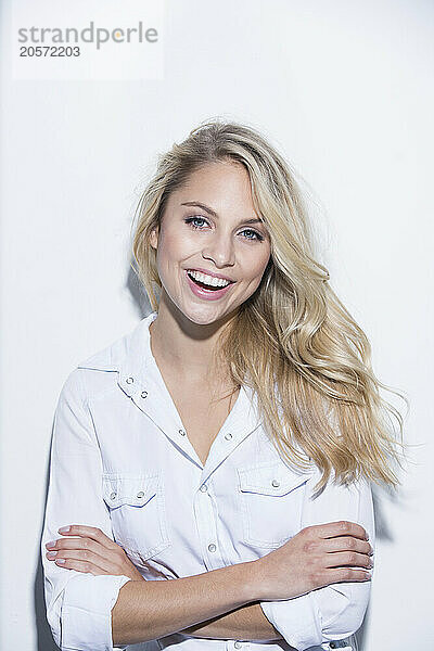 Smiling woman with arms crossed against white background