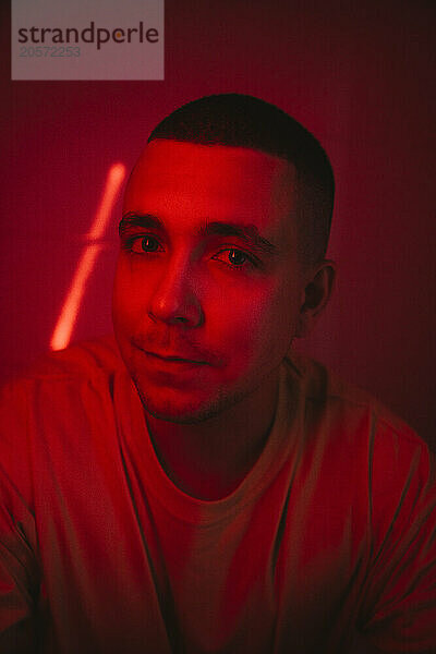 Serious man with buzz cut amidst red light