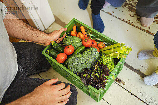 Man holding crate of fresh vegetables at home