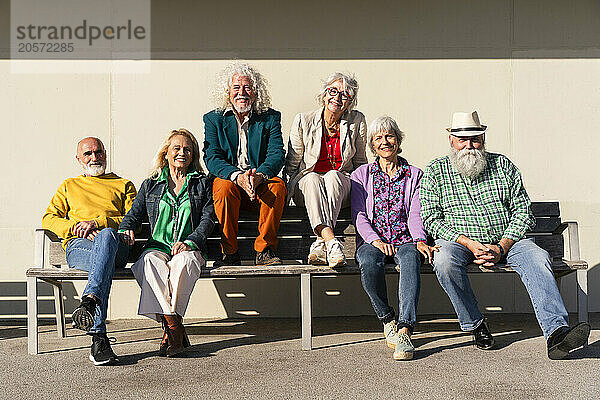 Happy retired men and women sitting together on bench