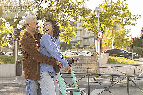 Happy woman standing by push scooter with boyfriend at park