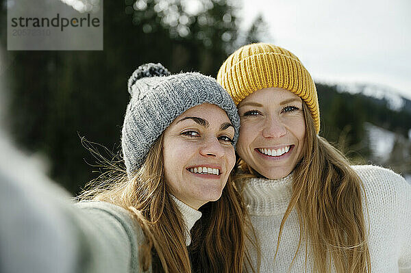 Cheerful friends in warm clothing taking selfie