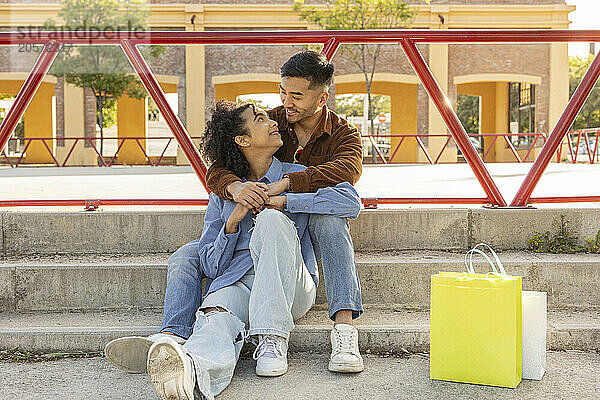 Happy young couple spending leisure time and sitting on staircase at park