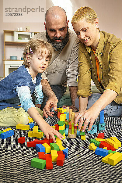 Daughter playing toy blocks with father and mother at home