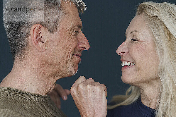 Smiling senior man with blond woman against blue background