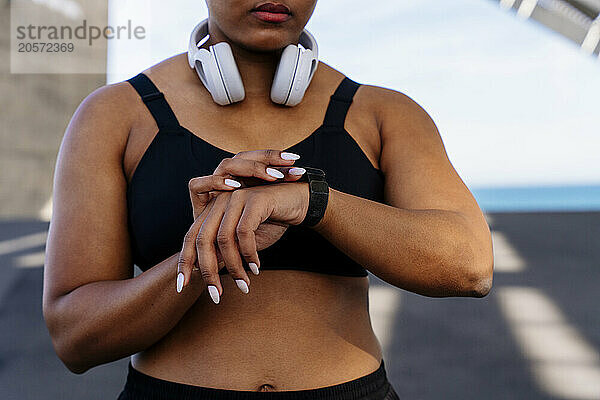 Sporty woman checking fitness tracker on road