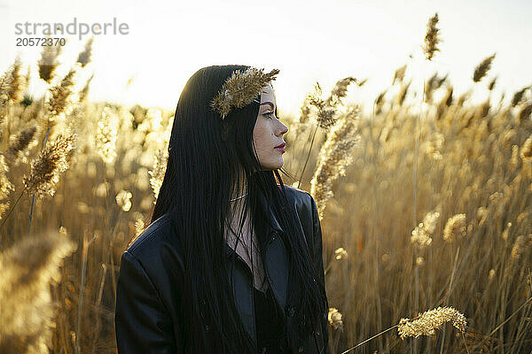 Young woman with crop plant in hair at field on sunny day