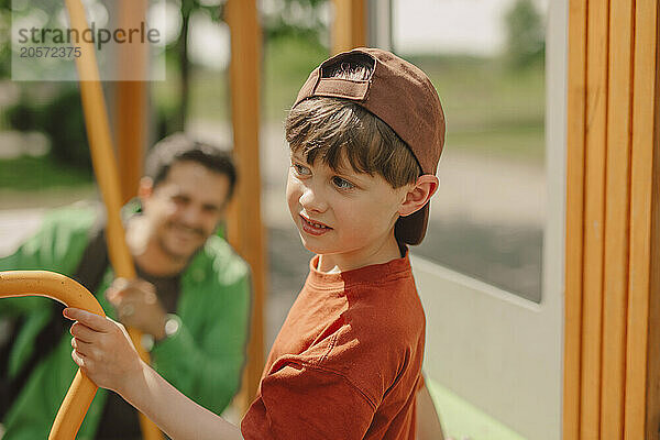 Cute boy standing near father at playground