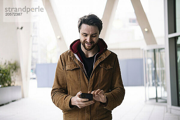 Smiling man text messaging on smart phone