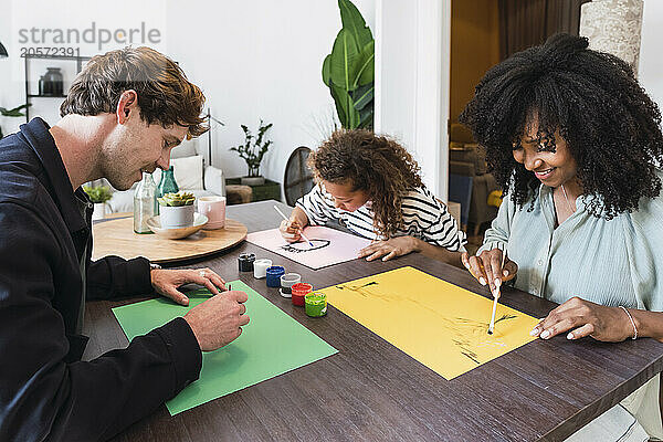 Family sitting at table drawing and painting together