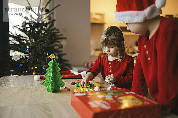 Siblings moulding shape for Christmas decoration from plasticine on table