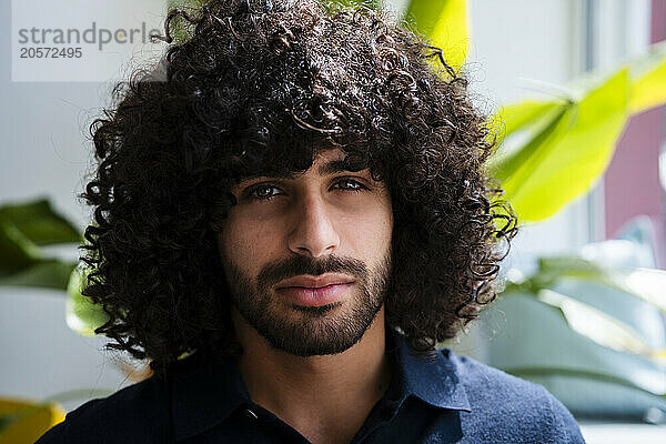 Confident young businessman with stubble and curly hair at office