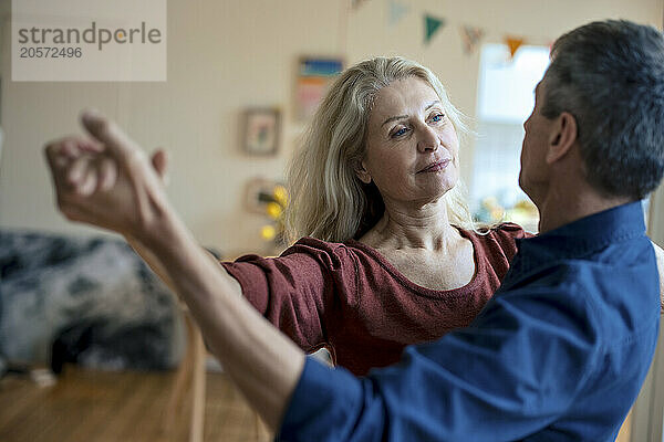 Senior couple holding hands and dancing at home