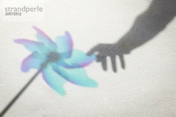 Shadow of woman's hand touching pinwheel toy