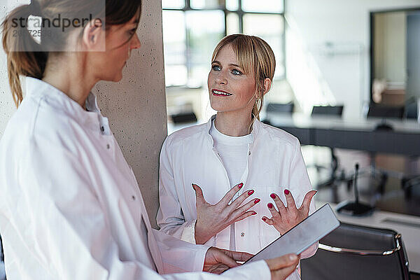 Confident female doctors standing with tablet PC discussing in hospital