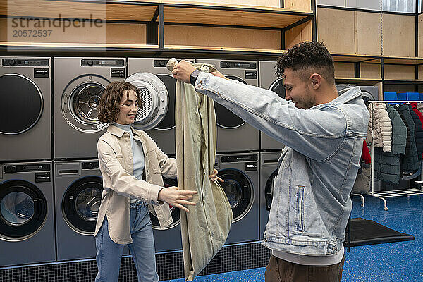 Young couple folding sheet together at laundromat