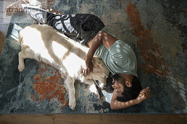 Young man sleeping with dog on carpet in living room at home