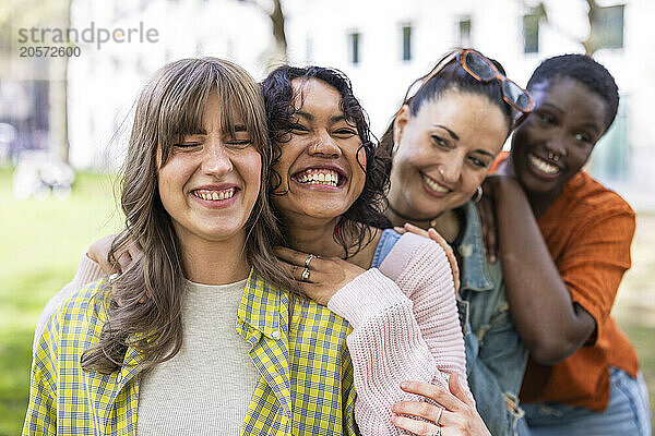 Cheerful women leaning on each other at park