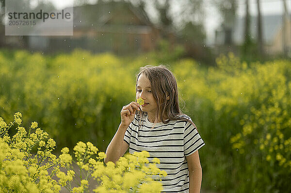 Girl wearing striped t-shirt and smelling flower in field