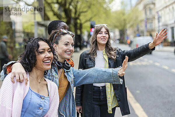 Female friends hailing ride on roadside in city