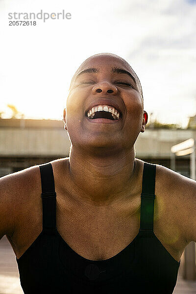 Cheerful bald woman laughing on sunny day