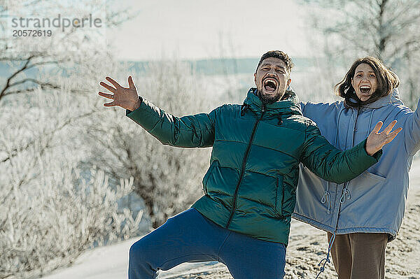 Playful couple screaming in winter forest