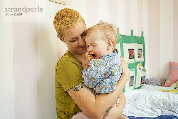 Smiling woman holding daughter at home