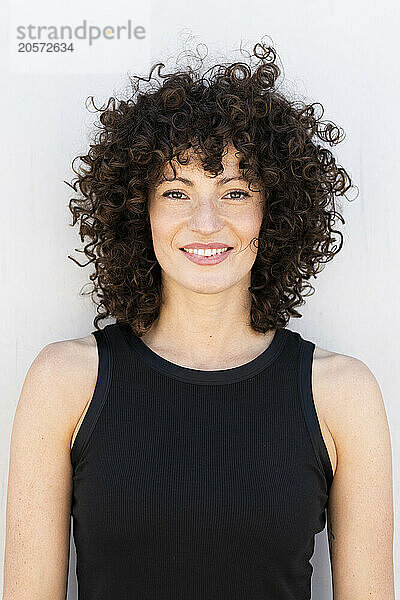 Smiling beautiful woman with curly hair wearing black tank top