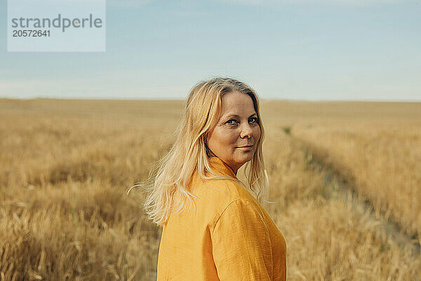 Mature blond hair woman in yellow shirt standing on wheat field