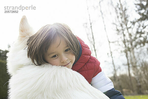 Boy leaning on White Swiss Shepherd Dog