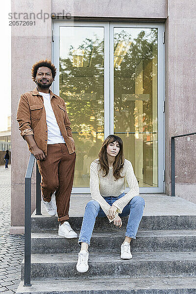 Confident couple on steps in front of building entrance