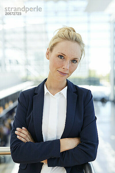 Smiling businesswoman standing with arms crossed at airport lobby