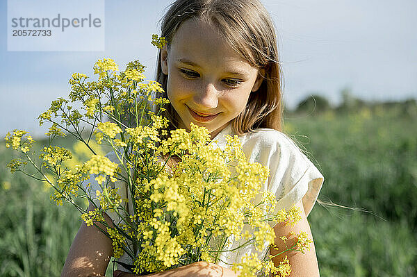 Cute girl holding bunch of flowers and standing in farm