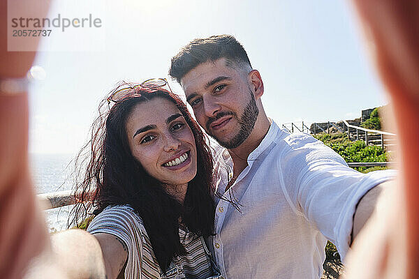 Smiling young couple taking selfie with each other