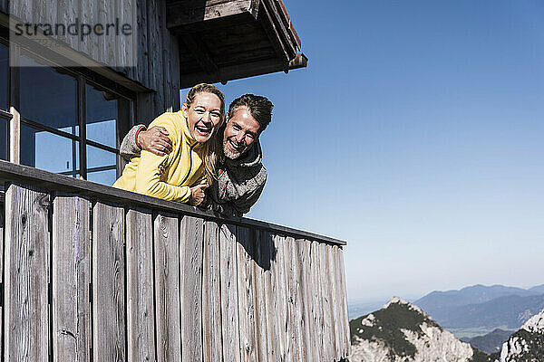 Cheerful couple spending leisure time at log cabin under blue sky in Tyrol