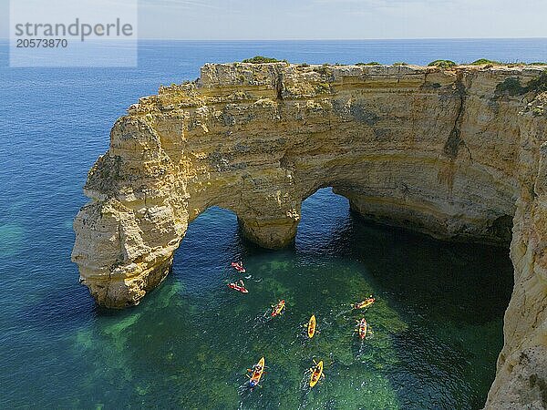 A rocky cliff juts out into the turquoise sea  where several colourful kayaks paddle on the water  aerial view  Praia da Marinha  double rock arch  Lagoa  Rocky Algarve  Algarve  Portugal  Europe