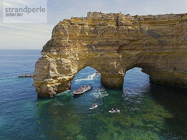 Large rock arch in the blue waters of the Algarve  Portugal  with several boats and tourists in the area  aerial view  Praia da Marinha  double rock arch  Lagoa  Rocky Algarve  Algarve  Portugal  Europe