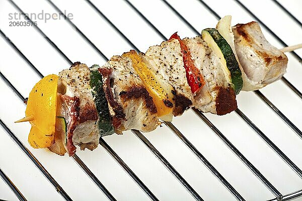 Grilled shashlik on a charcoal grate over a white background