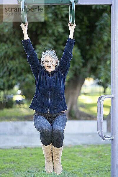 Woman in her sixties doing exercises in the park. Happy expression. Vitality concept