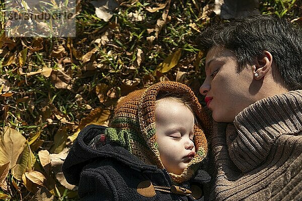 Mother and baby sleeping in the park on autumn leaves