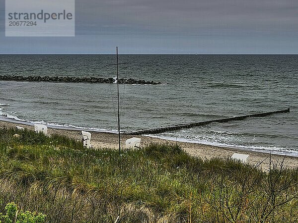 View over an extensive coastal landscape with beach chairs and a cloudy North Sea in the background  ahrenshoop  zingst  germany