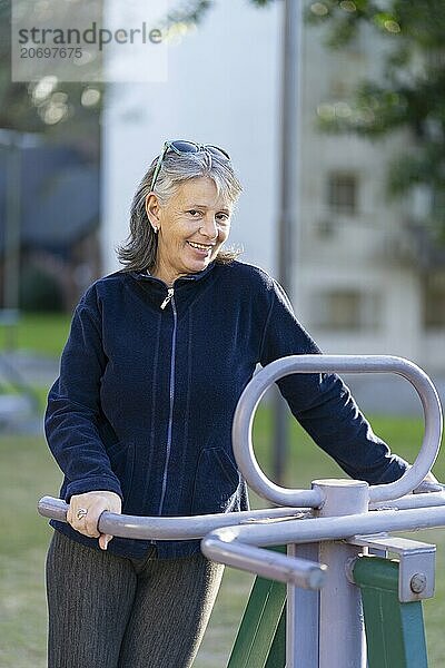 Woman in her sixties doing exercises in the park. Happy expression. Vitality concept