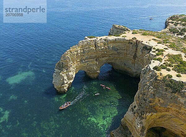 Natural arch formations on the coast  surrounded by clear water with boats passing underneath  aerial view  Praia da Marinha  double rock arch  Lagoa  Rocky Algarve  Algarve  Portugal  Europe