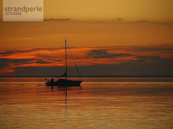 A sailing boat motors through the evening  past the island of Djurö in Lake Vänern. sailing boat after sunset on lake vänern in sweden