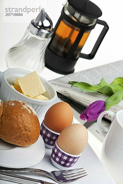 Eggs  bread rolls  butter and coffee on a white background