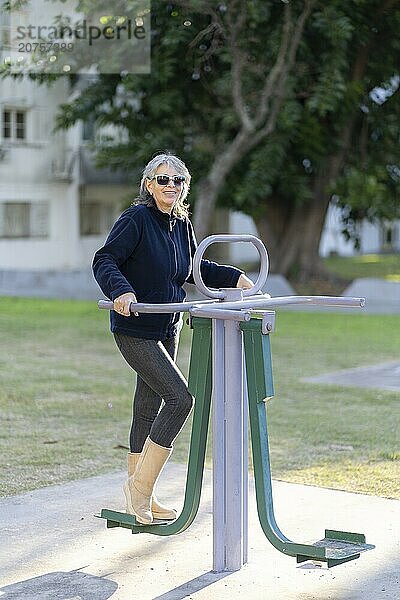 Woman in her sixties doing exercises in the park. Happy expression. Vitality concept