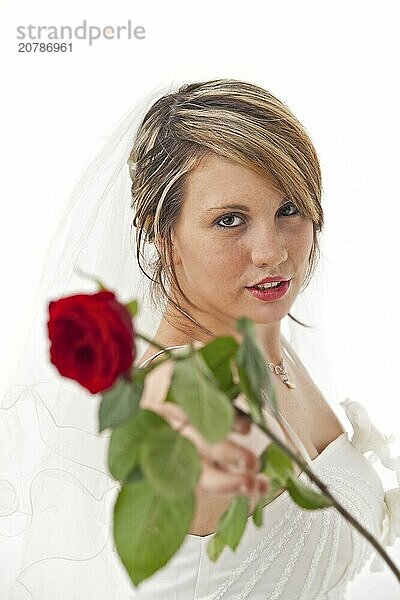 Beautiful young bride in a wedding dress with a veil holding a rose